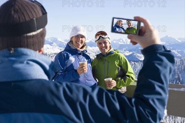 USA, Montana, Whitefish, Man photographing two women in mountain resort. Photo : Noah Clayton