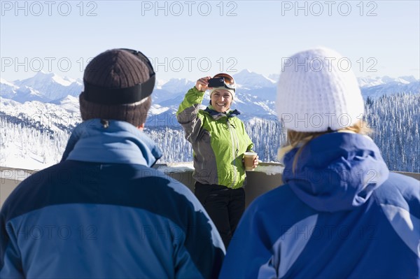 USA, Montana, Whitefish, Woman photographing friends in mountain resort. Photo : Noah Clayton