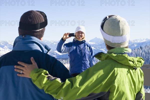 USA, Montana, Whitefish, Woman photographing friends in mountain resort. Photo: Noah Clayton