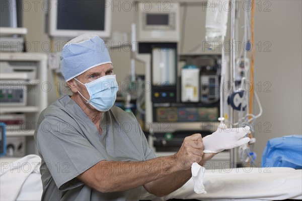 Surgeon putting on gloves. Photo : db2stock