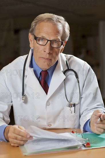 Portrait of male doctor reading files. Photo : db2stock