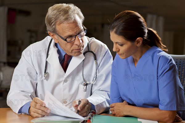 Doctors sitting at desk and reading files. Photo : db2stock