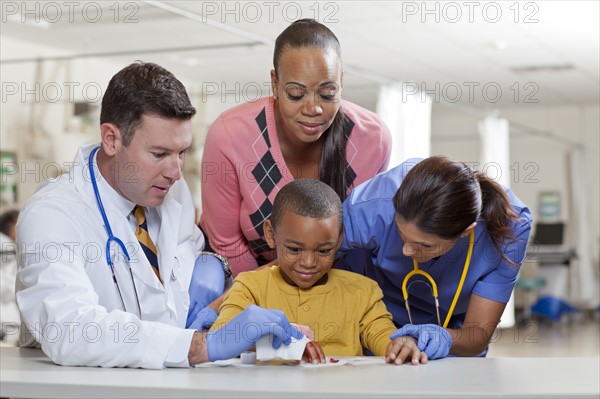 Doctors applying bandage on boy's (4-5) hand. Photo : db2stock