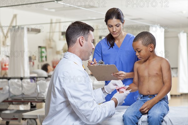 Doctors applying bandage on boy's (4-5) hand. Photo : db2stock