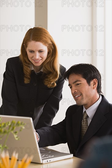 Businessman and businesswoman using laptop. Photo: Rob Lewine