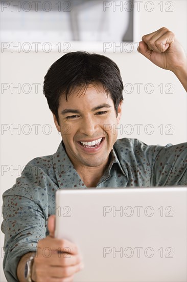 Businessman celebrating in front of laptop. Photo : Rob Lewine