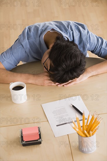 Businessman resting head on desk. Photo : Rob Lewine