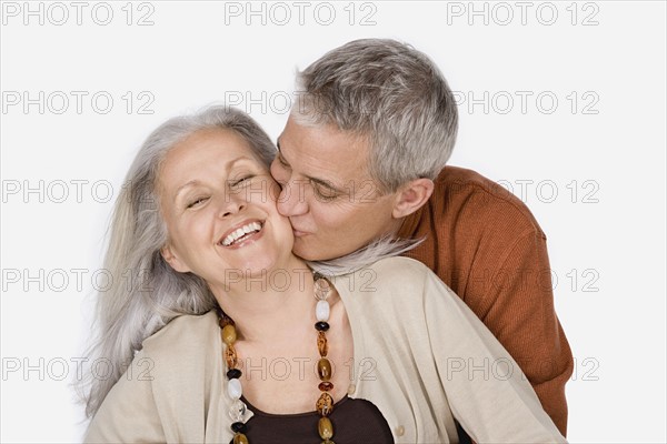 Studio shot of mature man kissing woman. Photo: Rob Lewine