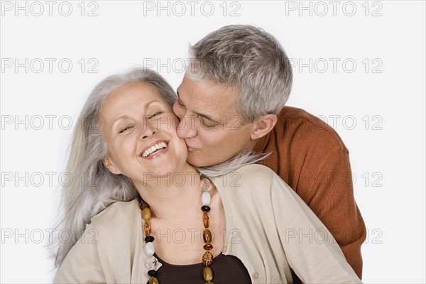 Studio shot of mature man kissing woman. Photo : Rob Lewine