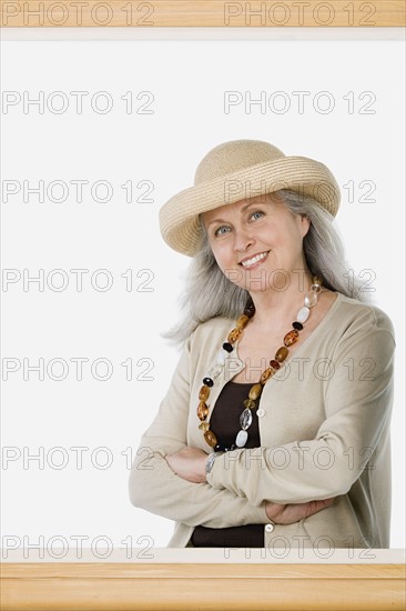 Studio portrait of mature woman behind picture frame. Photo : Rob Lewine