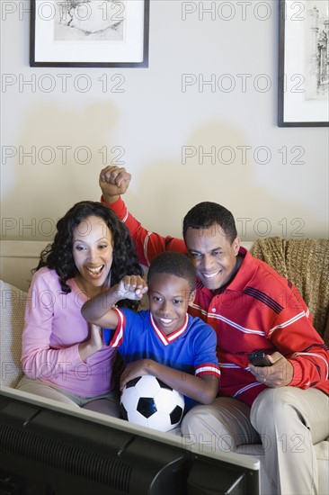 Parents with Son (12-13) watching sports on tv. Photo: Rob Lewine