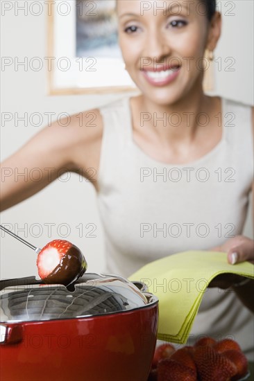 Woman dipping strawberries in chocolate mousse. Photo : Rob Lewine