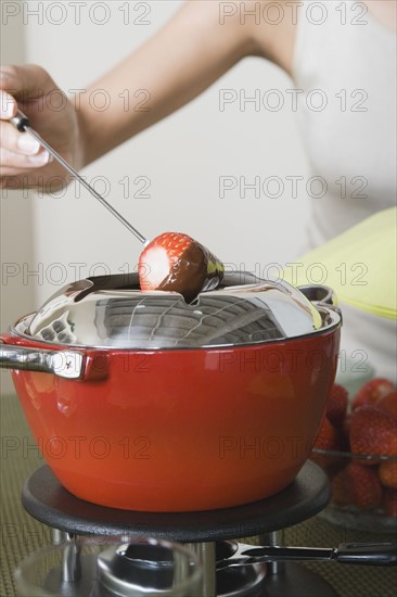 Woman dipping strawberries in chocolate mousse. Photo : Rob Lewine