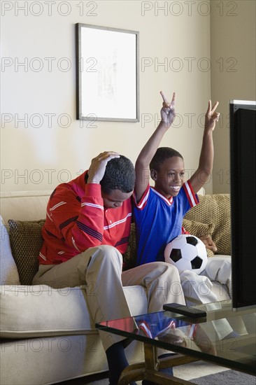 Father and Son (12-13) watching sports on tv. Photo : Rob Lewine