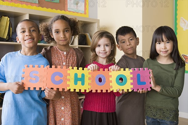 Portrait of schoolchildren (6-7) holding colorful letters. Photo : Rob Lewine