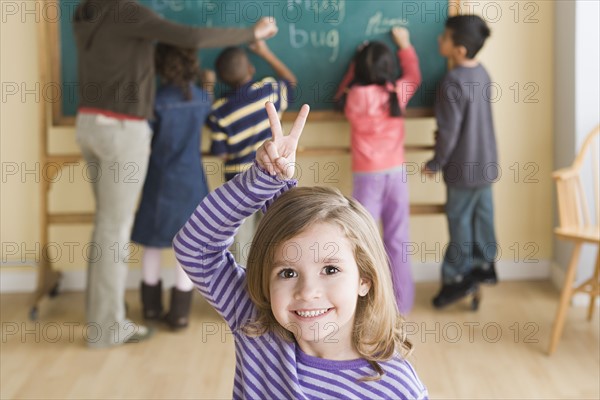 Portrait of smiling girl (6-7) with schoolmates in background. Photo : Rob Lewine