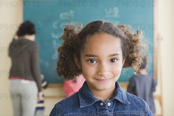 Portrait of smiling girl (6-7) with schoolmates in background. Photo : Rob Lewine