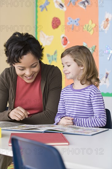 Teacher helping girl (6-7) in reading. Photo : Rob Lewine