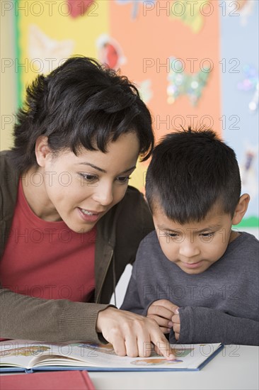 Teacher helping boy (6-7) to read. Photo : Rob Lewine