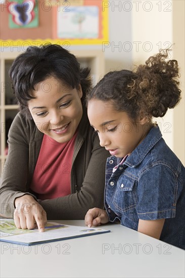 Teacher helping girl (6-7) to read. Photo: Rob Lewine