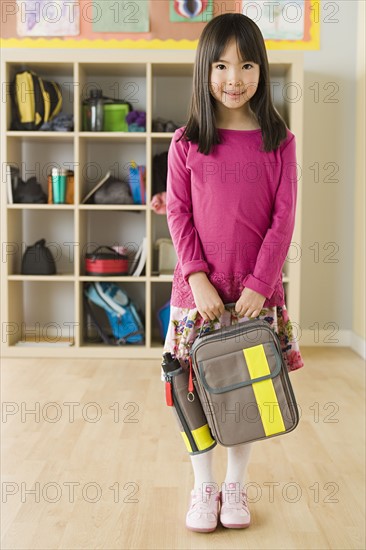 Portrait of schoolgirl (6-7) holding backpack. Photo : Rob Lewine