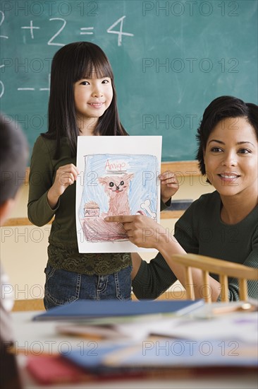 Girl (6-7) showing her drawing in classroom. Photo: Rob Lewine