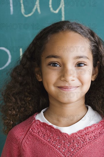 Portrait of schoolgirl (6-7) against blackboard. Photo : Rob Lewine