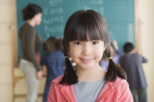 Portrait of smiling girl (6-7) with classmates in background. Photo : Rob Lewine