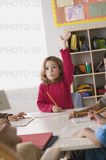 Girl (6-7) rising her hand in classroom. Photo : Rob Lewine