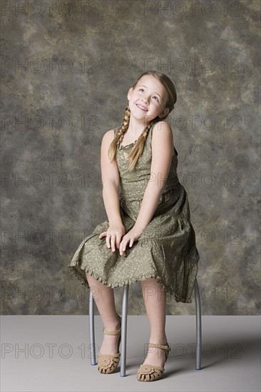 Portrait of smiling girl (8-9) sitting on stool. Photo : Rob Lewine