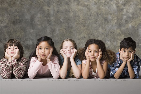 Children (6-7, 8-9) lying on floor, studio shot. Photo : Rob Lewine