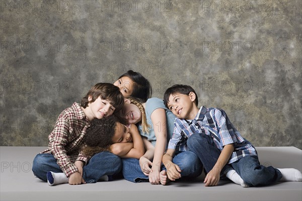 Tired children (6-7, 8-9) lying together, studio shot. Photo: Rob Lewine