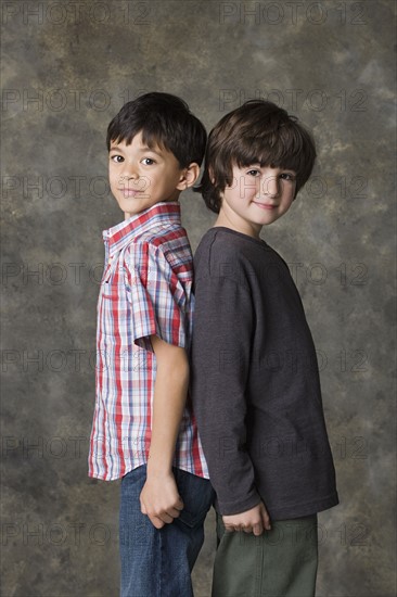 Two boys (6-7, 8-9) posing back to back, studio shot. Photo: Rob Lewine