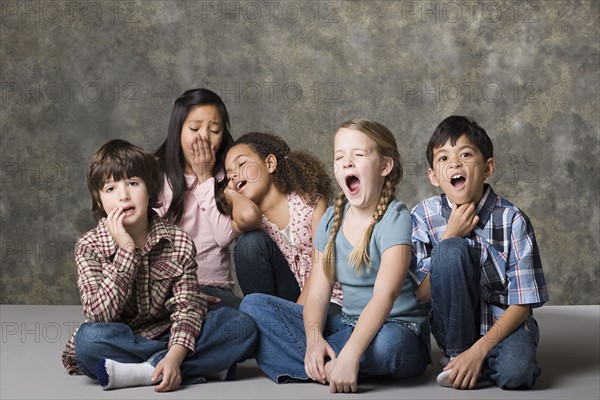 Tired children (6-7, 8-9) lying together, studio shot. Photo: Rob Lewine