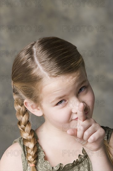 Portrait of smiling girl (8-9) pointing to camera, studio shot. Photo : Rob Lewine