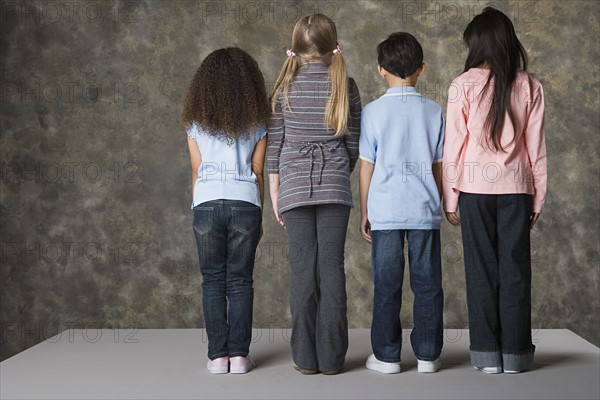 Rear view of children (8-9) standing, studio shot. Photo : Rob Lewine