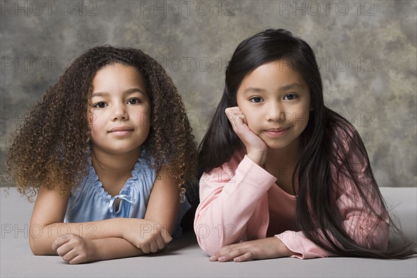 Portrait of two girls (8-9) looking at camera, studio shot. Photo: Rob Lewine
