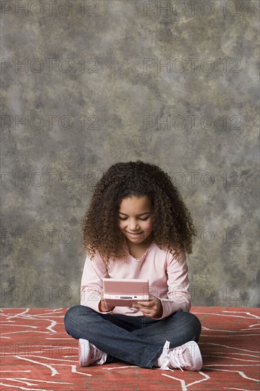 Girl (8-9) playing game, studio shot. Photo: Rob Lewine