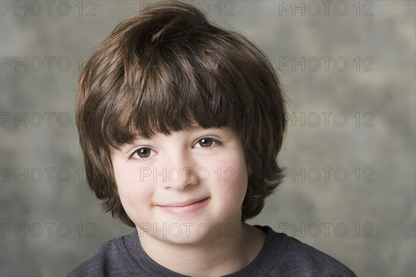 Portrait of smiling (6-7) boy, studio shot. Photo: Rob Lewine