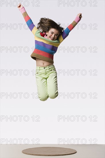 Happy girl (8-9) jumping, studio shot. Photo : Rob Lewine