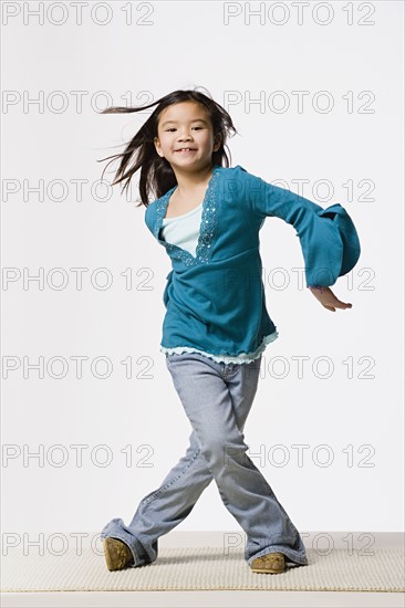 Smiling girl (8-9) dancing, studio shot. Photo: Rob Lewine
