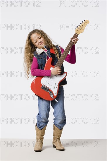 Studio shot of girl (8-9) playing electric guitar, studio shot. Photo : Rob Lewine