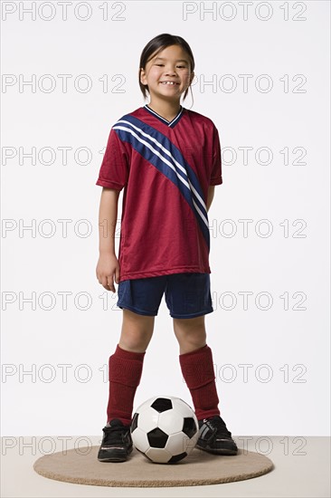 Smiling girl (8-9) wearing soccer uniform, studio shot. Photo: Rob Lewine