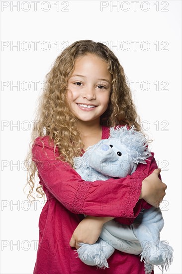 Portrait of smiling girl (8-9) embracing toy, studio shot. Photo : Rob Lewine