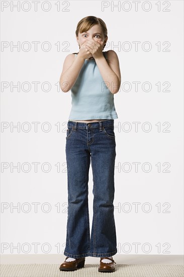 Smiling girl (8-9) covering her mouth, studio shot. Photo : Rob Lewine