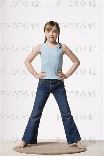 Portrait of girl (8-9) with hands on hips, studio shot. Photo : Rob Lewine
