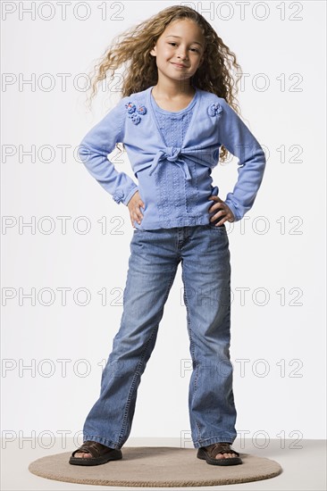 Portrait of girl (8-9) with hands on hips, studio shot. Photo: Rob Lewine