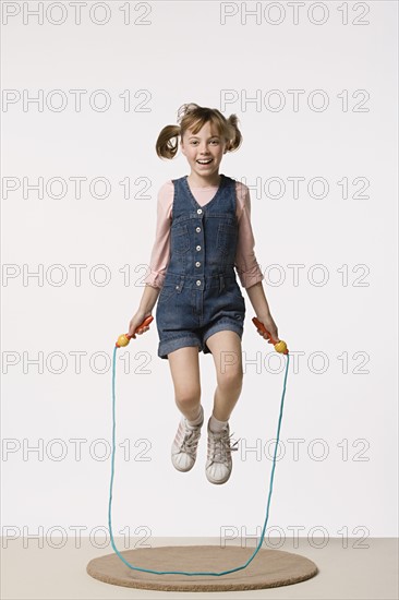 Studio portrait of girl (8-9) jumping on rope. Photo: Rob Lewine