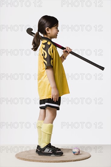 Studio portrait of girl (8-9) wearing sports clothes and holding hockey stick. Photo : Rob Lewine