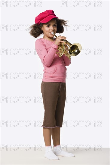 Studio portrait of girl (8-9) playing trumpet. Photo: Rob Lewine